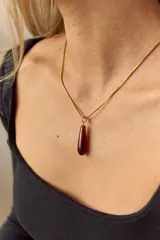 Collar dorado con cadena fina y dije colgante en forma de lágrima de piedra natural azul con vetas blancas.