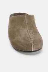 Zapato plano tipo mule destalonado confeccionado en serraje color marrón, con detalle de pespunte en el cuerpo y punta redonda.