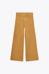 Pantalón de jean color ocre, de tiro alto y corte wide leg, con bolsillos delanteros tipo parche y cierre frontal con cremallera y botón metálico.