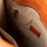 Cartera chica color habano, confeccionada en PU. Tiene acceso con cierre, un bolsillo interno con cierre, un bolsillo interno abierto y un bolsillo externo con cierre. Cuenta con asas fijas con diseño trenzado y correa regulable.