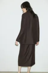 Blazer marrón de corte entallado, con solapas de pico, cierre de un botón, hombreras, bolsillos delanteros de parche, puños con abertura y botón, abertura trasera y forro interior.