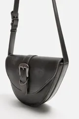 Bandolera negra de cuero sintético con hebilla metálica al frente y correa ajustable.