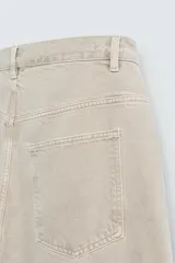 Pantalón de jean color beige, de corte amplio y tiro alto, con cinco bolsillos, efecto lavado y cierre frontal con botones.