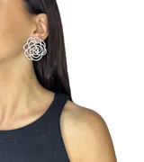 Par de aros rígidos con forma de flor calada, con incrustaciones de circonias.