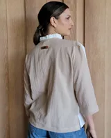 Camisa de manga larga color blanco y beige, con cuello con volados y cierre frontal con botones.