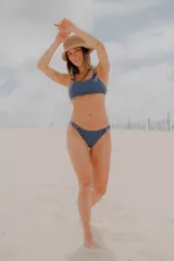 Conjunto de bikini azul con corpiño de breteles finos y hebillas metálicas en los tirantes. La bombacha es colaless y también tiene hebillas metálicas en los laterales.