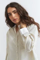 Camisa corta de poliéster a rayas verticales celestes y blancas, con cuello y puños blancos.