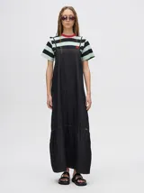 Vestido midi de denim algodón color marrón, con escote recto y tirantes finos ajustables con lazos. El corte es suelto y termina con un ruedo con semi-volado.