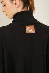 Sweater negro oversize de tejido de punto, con cuello alto y detalle de costuras a la vista.