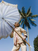 Chaqueta de algodón color arena, con cuello extendido, cierre con botones y cinturón para atar en la cintura.