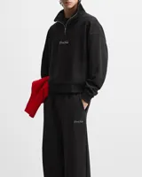 Buzo negro de cuello alto con cierre metálico y logo bordado en el pecho.