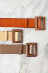 Cinturón azul marino de cuero con hebilla cuadrada de madera.