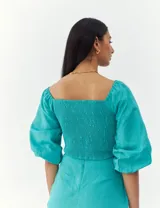 Top turquesa con escote cuadrado, mangas abullonadas y cuerpo fruncido.