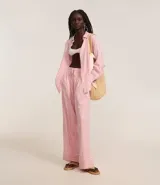 Pantalón de cambraia color rosa con rayas verticales blancas, de corte recto y cintura alta con elástico y lazo.