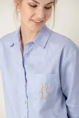 Camisa de lino color gris claro con bordado de monograma PEC en el bolsillo.