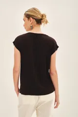 Remera negra de viscosa con calce suelto, escote redondo, manga corta y estampado frontal con bordado de lentejuelas doradas.