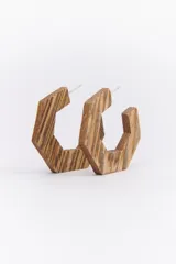 Par de aros de madera con forma hexagonal y diseño de líneas horizontales en tonos marrones. Cierre tipo pin.
