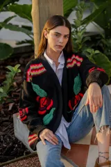 Cárdigan negro de tejido de punto con bordados de rosas rojas y hojas verdes. Presenta detalles bordados multicolores en hombros y puños.