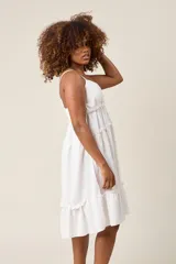 Vestido corto lila con breteles finos, escote en V con botones y falda escalonada con volados.