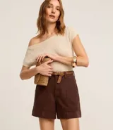 Short de mujer de sarga color beige claro, tiro alto, con pespuntes contrastantes en color blanco o crema. Presenta un corte regular y bolsillos delanteros y traseros.