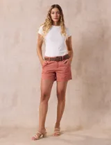 Short de jean azul oscuro con pretina con pasadores, botón y cierre. Delantera con bolsillos. Botón en bolsillos traseros. Incluye cinturón trenzado marrón con hebilla redonda dorada.
