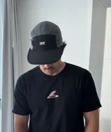 Remera negra de manga corta con estampado gráfico en la espalda que incluye un sol amarillo, una estrella de mar, una flor, una ola con el logo 'Brokers' y formas abstractas en tonos pastel, junto al texto 'VITAMIN SEA'.