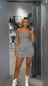 Vestido corto plateado con brillos, strapless y corte ajustado.