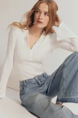 Body blanco de punto acanalado, con escote redondo, tapeta de botones y mangas largas acampanadas.