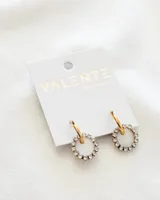 Par de aros dorados con dije circular blanco con incrustaciones de strass. Cierre de gancho. Diámetro del aro: 1,5cm. Diámetro del dije: 1,5cm. Material del aro: Acero.