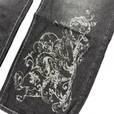 Pantalón jean negro con estampado de arabescos en color gris, de tiro bajo y corte baggy.