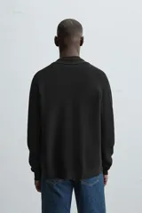Cárdigan negro de punto con cuello solapa, manga larga y cierre frontal con botones.