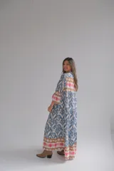 Vestido largo celeste con estampado abstracto en tonos azules, marrones y rosados. Tiene cuello mao, mangas 3/4 acampanadas y cierre frontal con botones.