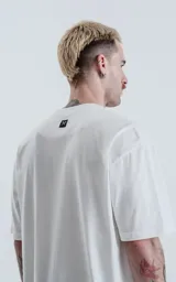 Remera oversize de algodón premium color blanco tiza, con cuello redondo rib al tono y hombros caídos.