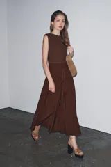 Vestido midi marrón con cuello barco y manga sisa. Presenta un corte a la altura de la cintura con detalle de trabilla y lazo del mismo tejido. Cierre lateral con cremallera oculta.