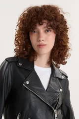 Campera biker negra de cuero sintético con cuello solapa, cierre cruzado con cremallera, bolsillos con cremallera y cinturón ajustable.