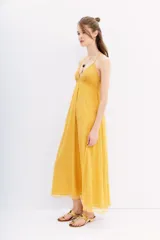 Vestido largo color mostaza, con breteles finos cruzados en la espalda y detalles de canutillos bordados.