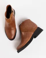 Botín de cuero negro con detalle de cuero texturizado en el talón y tira de gamuza en el lateral. Tiene cierre en el lateral interno y suela de goma.