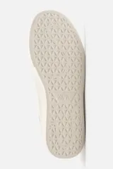 Zapatillas deportivas blancas con detalle de color a contraste en el talón y suela con acabado irregular.