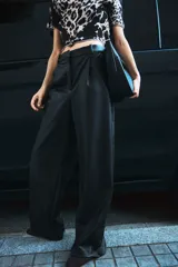 Pantalón de vestir negro de cuero sintético, de tiro alto, corte ancho y pinzas.