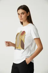 Remera blanca de algodón con cuello redondo y estampado abstracto en tonos marrones, dorados y rojizos.