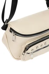 Riñonera color crema con correa ajustable negra, múltiples bolsillos con cierre y tachas decorativas.