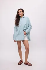 Camisa oversize a rayas verticales color amarillo y blanco, con cuello camisero, manga larga y cierre frontal con botones.