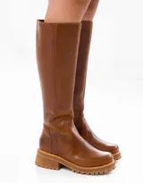 Bota de caña alta color marrón, confeccionada en cuero vacuno. Tiene suela de goma sport artesanal, cierre YKK del lado interno y horma de punta redonda.