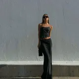 Conjunto de top con tirantes finos y falda larga con tajo lateral, ambos de seda color negro.
