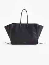 Bolso tote negro de cuero vacuno con textura granulada. Presenta cierres funcionales en los laterales para expandir el espacio y dos asas de mano. Incluye un tag colgante con aplique metálico y un tirador de cremallera con forma de figura.