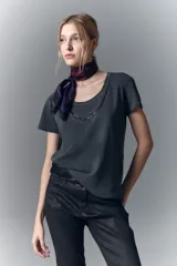 Remera blanca de algodón con cuello redondo y aplique de cadenas metálicas y strass en el escote.