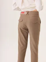Pantalón de vestir color marrón, corte cigarette (pierna angosta) con tajo en el bajo. Presenta una cintura elástica ancha de color beige claro.
