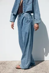 Pantalón de jean azul oscuro, de tiro medio, corte ancho y largo, estilo jogger con cintura elástica ajustable con cordones, bolsillos delanteros de vivo y bolsillos de parche en la espalda.