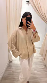Camisa color beige de lurex, de corte holgado y mangas largas con puños abotonados.