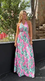 Vestido largo con estampado de hojas en tonos rosa y verde, escote halter y cintura elastizada.